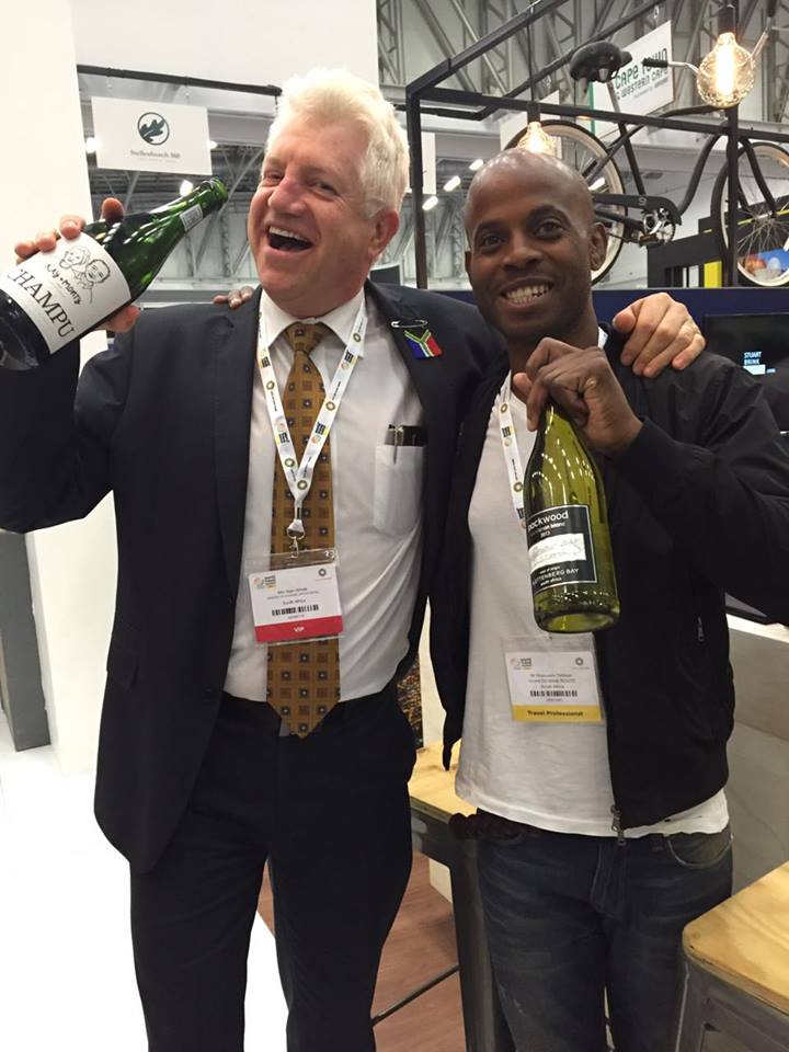 Alan Winde, Western Cape Minister of Economic Opportunities and Ntakuseni from Soweto Wine Tours toast the Plett Winelands at the Wesgro stand at WTM with local wines Kay & Monty, Luka and Packwood.