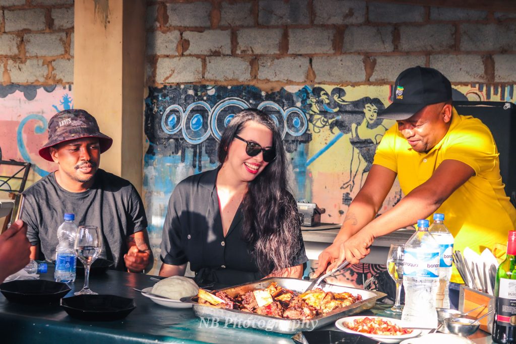 From left to right: Now this is how we role – Majozi and Daniela Ing enjoying the Tshisanyama experience with Thulani ‘Barco’ Ntsukwana.